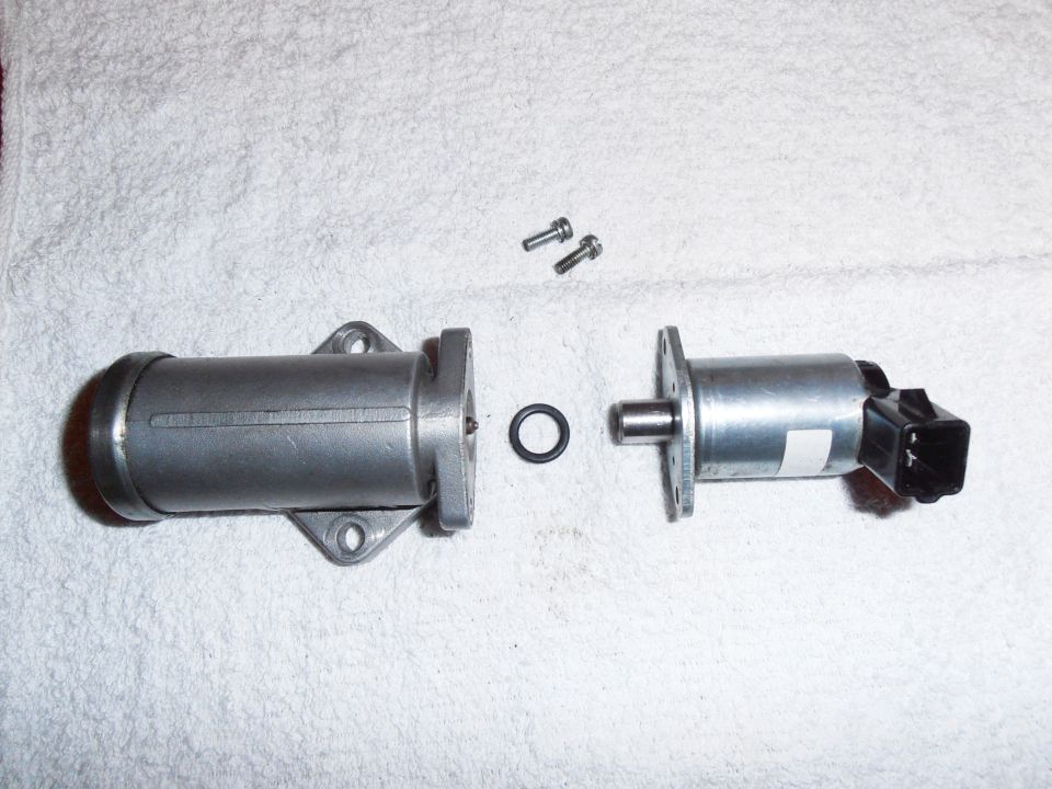 Disassembled idle air control valve with two screws and an O-ring on a white towel