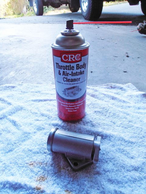 1990 Ford Bronco - A can of throttle body cleaner and a metal component are laid out on a towel, with a vehicle visible in the background.