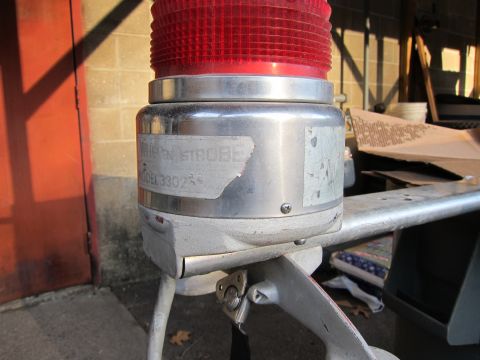 1991 Ford LTD Crown Victoria - A close-up view of a red strobe light mounted on a metal frame, with a partially legible label.