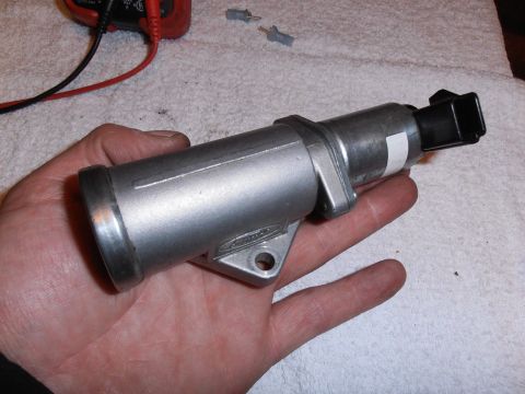 1990 Ford Bronco - A silver automotive part, possibly an idle air control valve, is held in a person's hand.
