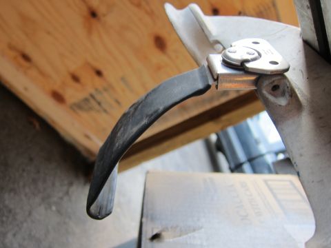 1991 Ford LTD Crown Victoria - This image shows a close-up of a car door handle mechanism, a black curved lever attached to metal components.