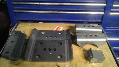 1989 Ford Bronco - Several metal brackets and rubber components are arranged on a surface in front of a blue toolbox.