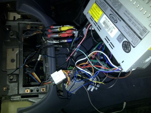 2000 Ford Crown Victoria - The complex wiring behind a car's stereo system is exposed, showing numerous cables and connections.