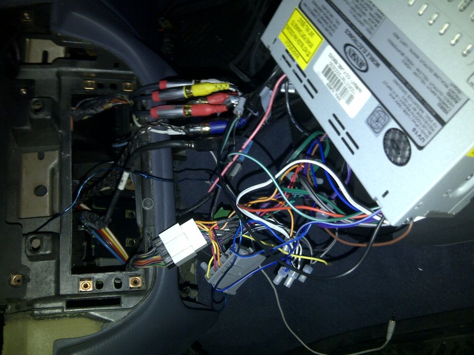 Car stereo wiring mess with RCA cables and a Jensen head unit