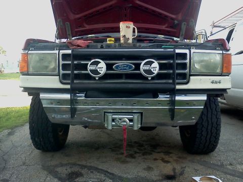 1989 Ford Bronco - This Ford truck features a chrome bumper, a bull bar with auxiliary lights, and a winch mounted below.