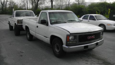 1989 Ford Bronco - A white GMC pickup truck is parked on asphalt, with two other vehicles visible in the background.