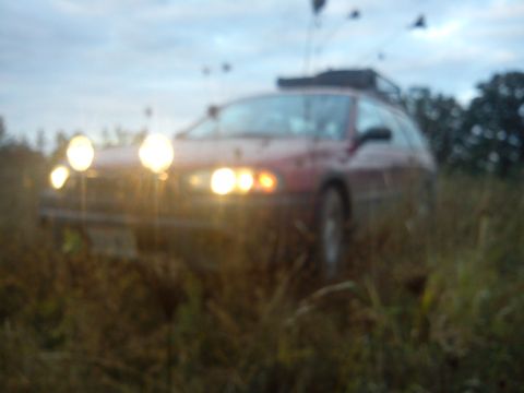 1998 Subaru Legacy - A red 1998 Subaru Legacy station wagon is seen in a grassy field with its auxiliary lights on.