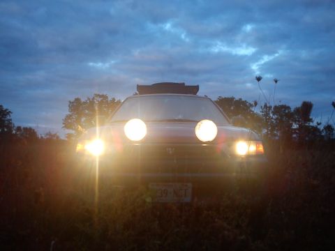 1998 Subaru Legacy - A Subaru Outback with auxiliary lights on is parked in a field at dusk. The license plate reads '39-NCT'.