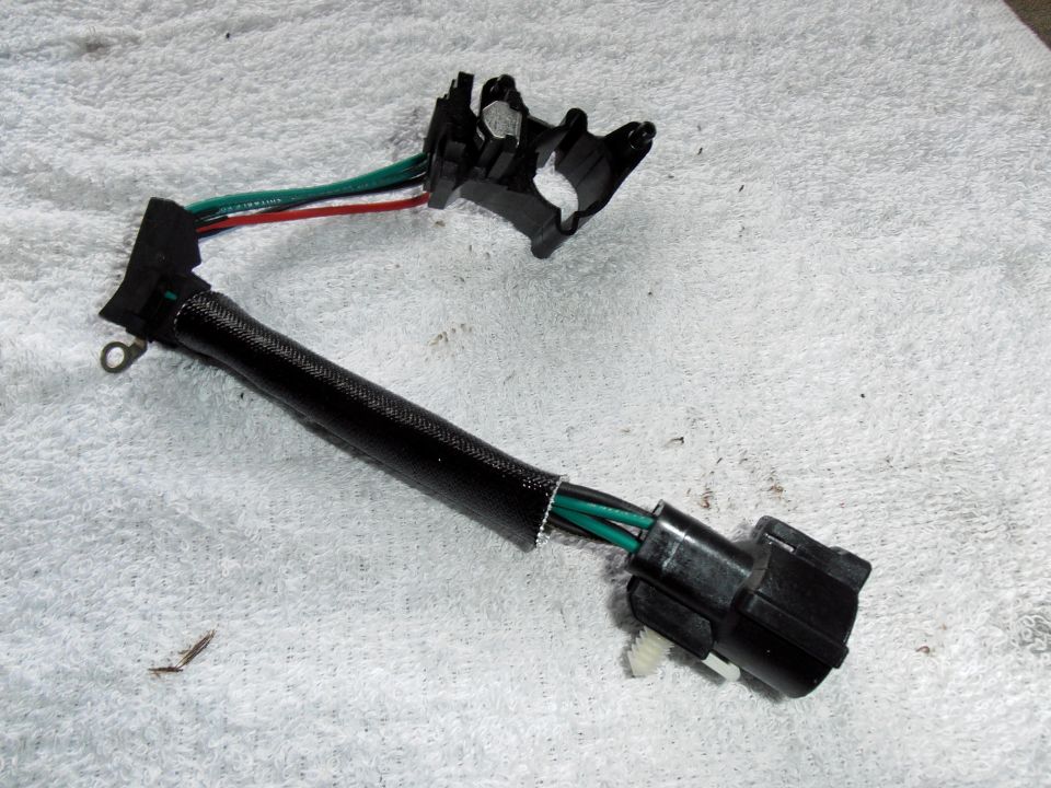 Wiring harness with black protective sleeve and multiple colored wires leading to a black connector