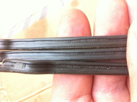 1998 Ford Crown Victoria - Rubber belts with embossed text are held by fingers, showing part numbers.