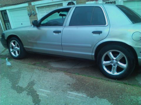 1999 Ford Crown Victoria - Side profile of a silver 1999 Ford Crown Victoria, aftermarket chrome wheels.