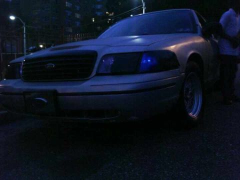 1999 Ford Crown Victoria - Silver Ford Crown Victoria with custom headlights and wheels is parked at night.