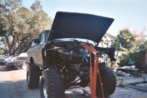 1978 Ford Bronco - This lifted truck is undergoing an engine swap, with the hood open and the engine being supported by an engine hoist.
