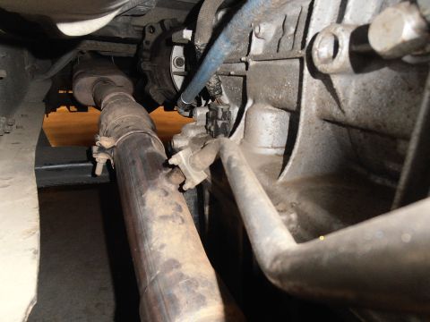 1990 Ford Bronco - Underside view of vehicle exhaust pipe and transmission housing components.