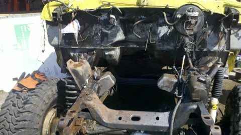 1978 Ford Bronco - The chassis and engine bay of a yellow 1978 Ford Bronco, showing suspension and drivetrain components.