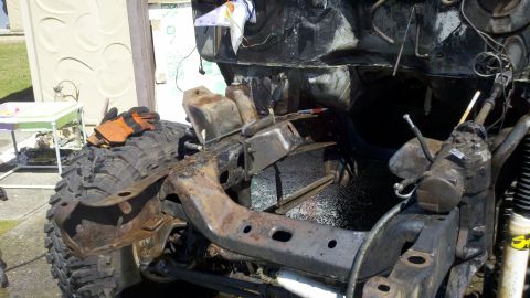 1978 Ford Bronco - The front chassis and suspension of a vehicle are shown, with a large tire and some tools in the foreground.