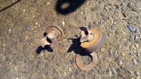 1978 Ford Bronco - Broken metal parts and a tire fragment lie on a gravel surface.
