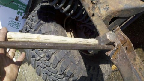 1978 Ford Bronco - A mechanic uses a hammer and bar to work on a vehicle's suspension component.