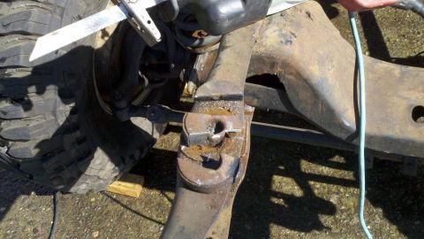 1978 Ford Bronco - Cutting a rusty suspension part with a reciprocating saw. The image shows a close-up of the component and a tire.