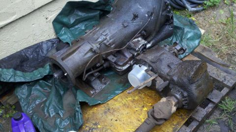 1978 Ford Bronco - Transmission and transfer case assembly, oily, on tarp and wood.
