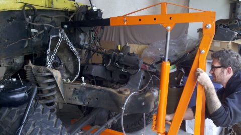 1978 Ford Bronco - Engine hoist in use during engine removal from a yellow vehicle.