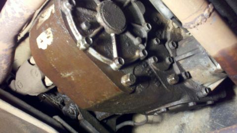 1978 Ford Bronco - Close-up view of a vehicle's transfer case, with a rusty exhaust pipe visible above it.