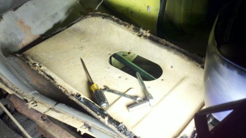 1978 Ford Bronco - Tools are laid out on the interior floor of a vehicle, near an access panel.