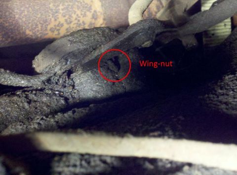 1978 Ford Bronco - A close-up view of greasy mechanical components on the underside of a vehicle, with a wing-nut circled and labeled.