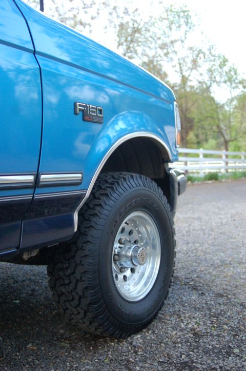 1992 Ford F-150 - Close-up of the fender badge and wheel on a blue 1992 Ford F-150 truck.