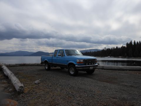 1992 Ford F-150 - Blue 1992 Ford F-150 parked by a lake under a cloudy sky.