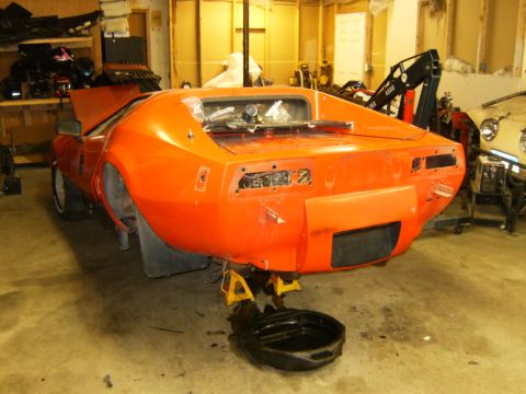 2000 Ford E350 - This orange sports car is in a garage, raised on jack stands with its rear end exposed for maintenance.