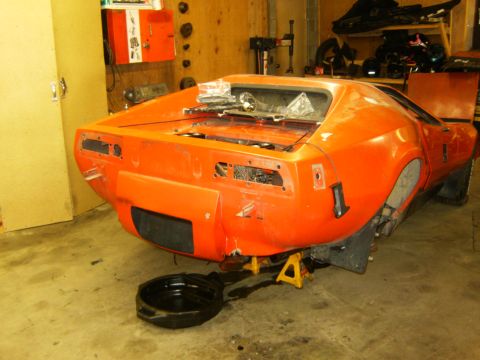 2000 Ford E350 - Orange sports car body undergoing repairs in a garage setting.