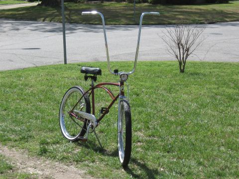 1994 Ford Bronco - A red cruiser bicycle with distinctive tall chrome handlebars sits on a grassy lawn.