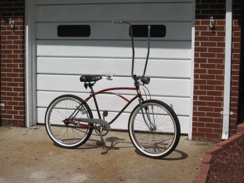 1994 Ford Bronco - A red cruiser bicycle with whitewall tires and tall handlebars is parked on a concrete driveway.