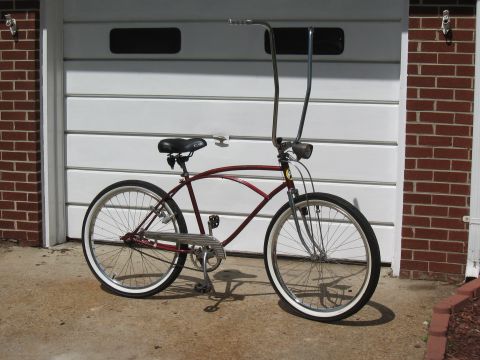1994 Ford Bronco - A maroon cruiser bicycle with tall handlebars and whitewall tires is parked in front of a white garage door.