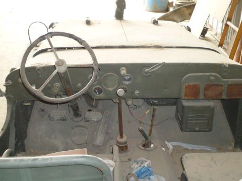 1986 Ford Bronco - The interior of a dusty, olive drab Jeep shows a worn steering wheel and dashboard instrumentation.