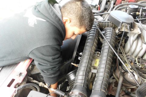 1994 Ford Bronco - A person is working on the engine of a vehicle, focusing on the air intake system.