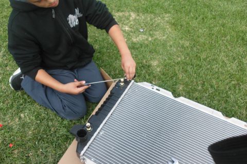 1994 Ford Bronco - A person works on a car radiator, which is a component part, not a whole vehicle.
