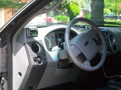 2008 Ford F-150 - The interior of a truck shows a gray dashboard with a Ford logo on the steering wheel.