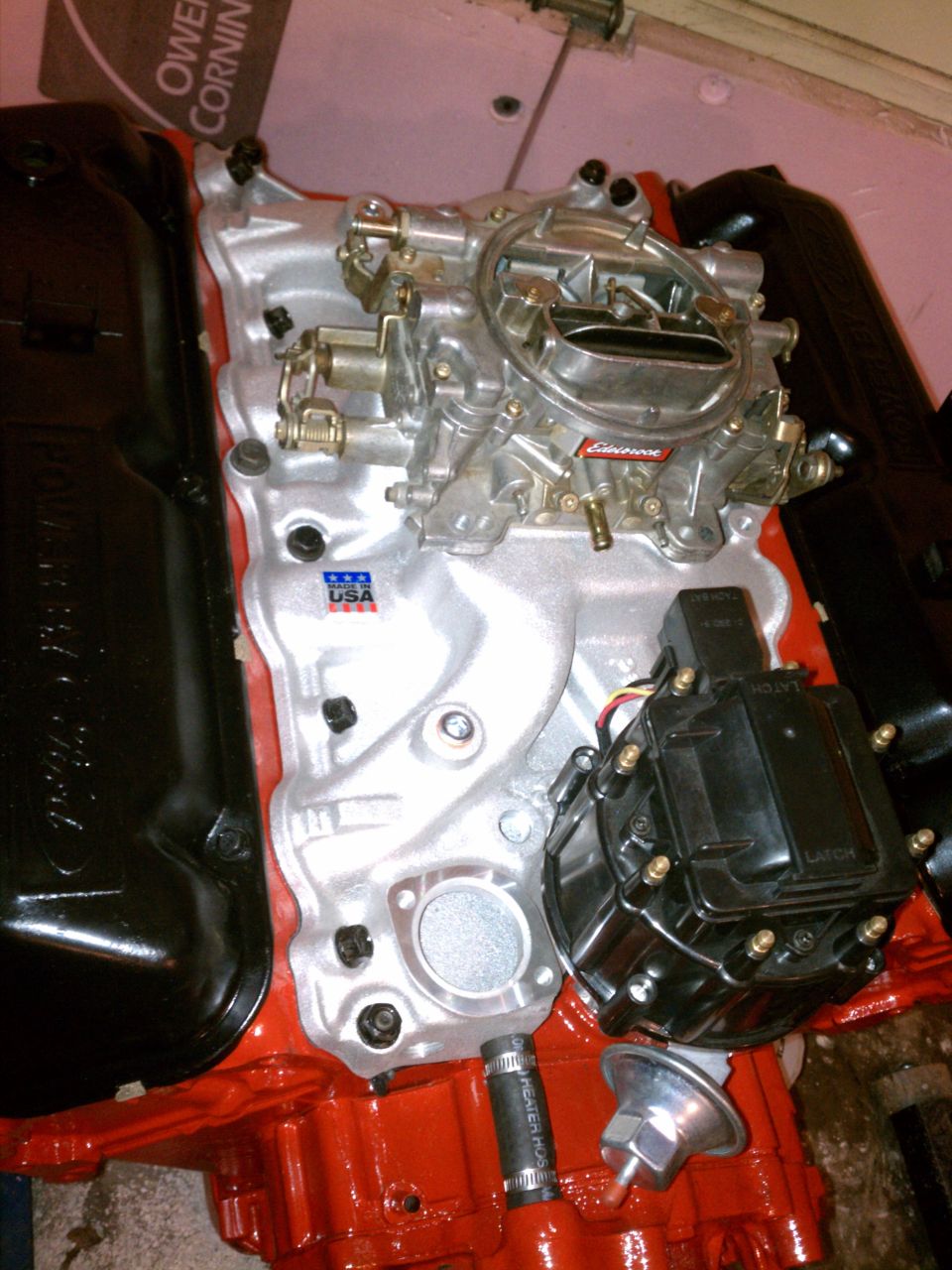 Engine intake manifold with carburetor and distributor, red engine block, black valve covers