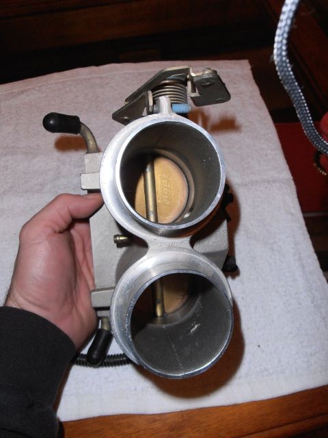 1990 Ford Bronco - A hand holds a throttle body, revealing the 'BBK' manufacturer's mark inside.