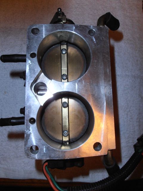 1990 Ford Bronco - A close-up view of a dual throttle body assembly, showing the internal butterfly valves and mounting points.