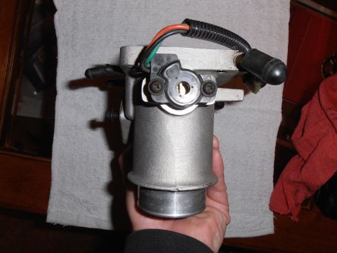 1990 Ford Bronco - A throttle body part is shown, held in a person's hand against a towel background.