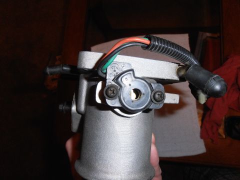 1990 Ford Bronco - A hand holds a throttle body assembly with electrical connectors and wiring visible.