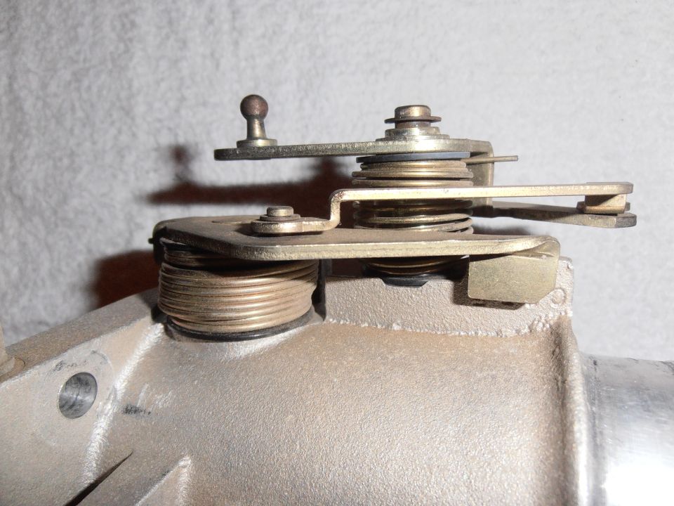 Closeup of carburetor throttle linkage mechanism on cast metal housing