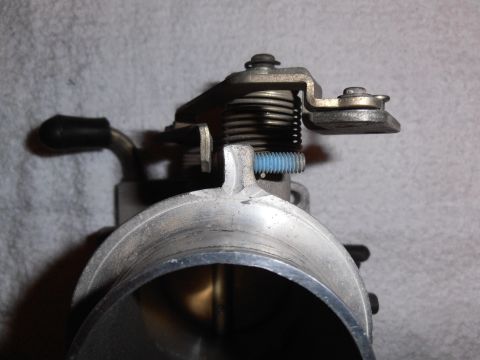 1990 Ford Bronco - Close-up view of a throttle body assembly, showing the spring mechanism and a blue bolt.