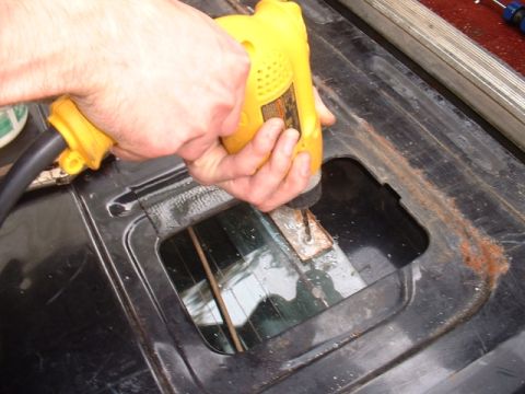 1986 Ford Bronco - Drilling a hole in the tailgate of a vehicle, with visible rust around the opening.