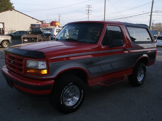1995 Ford Bronco XLT with red and grey paint, aftermarket wheels, and a black bug deflector