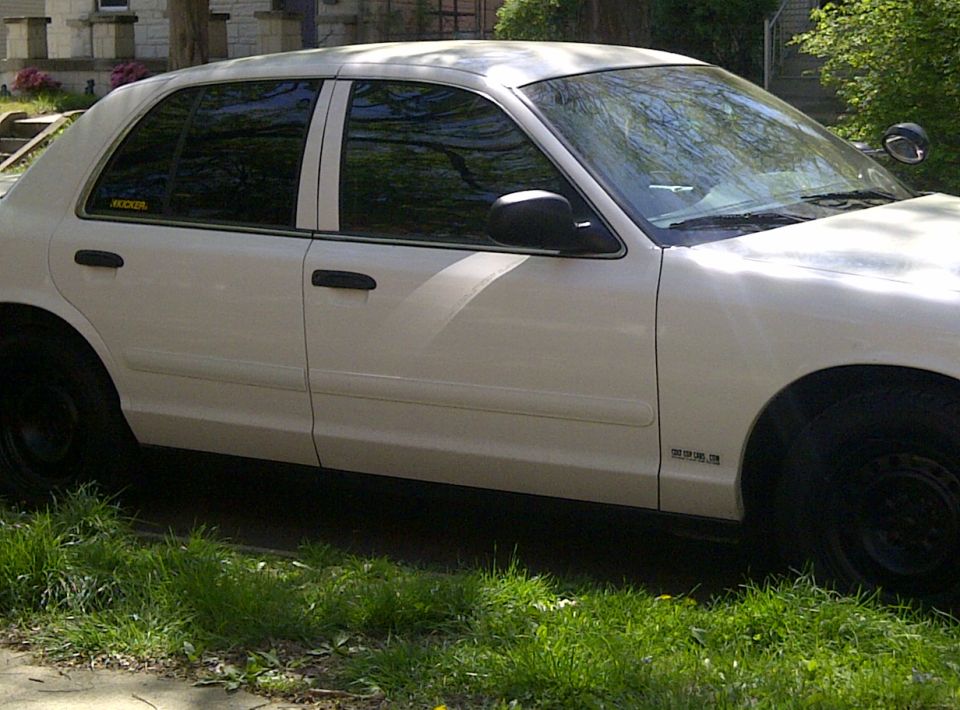 Side view of a white sedan with tinted windows and black steel wheels. A small sticker is on the rear door window