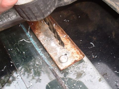 1986 Ford Bronco - Close-up of a rusty metal bracket with metal shavings, likely from a repair or modification process.